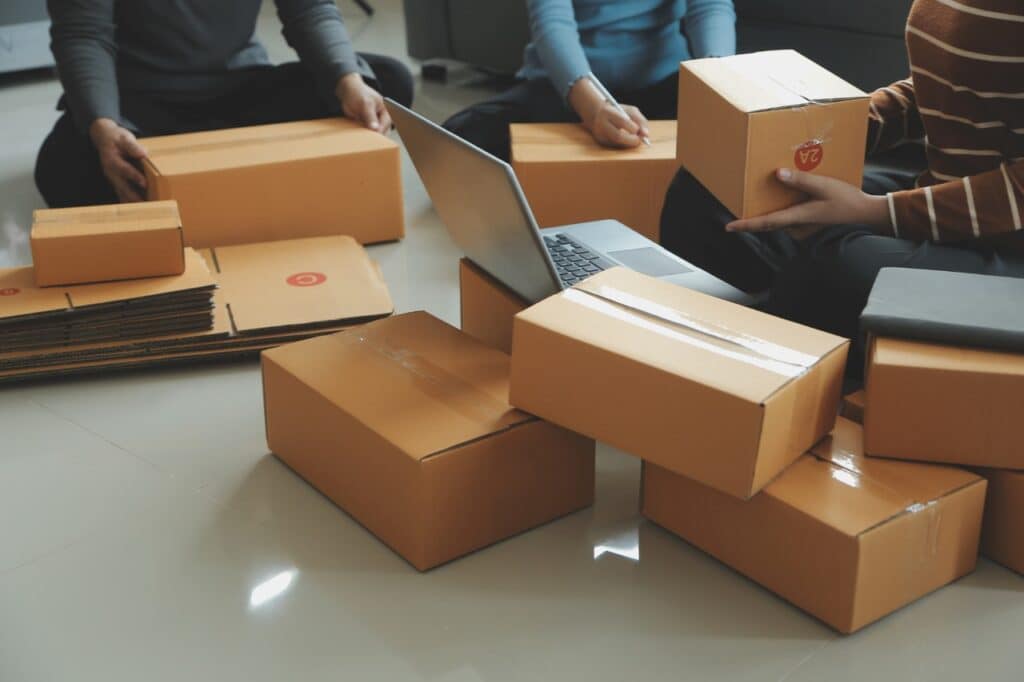 Team packing ecommerce orders with boxes and a laptop